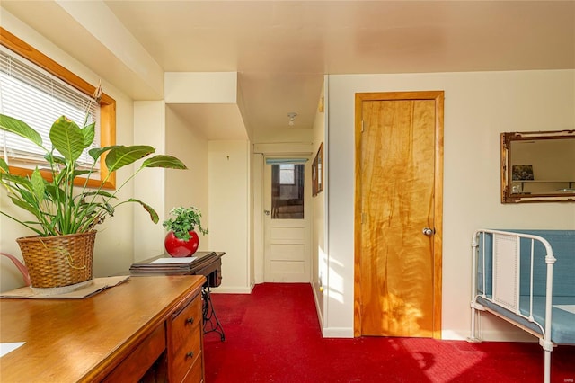 hallway featuring baseboards and dark colored carpet