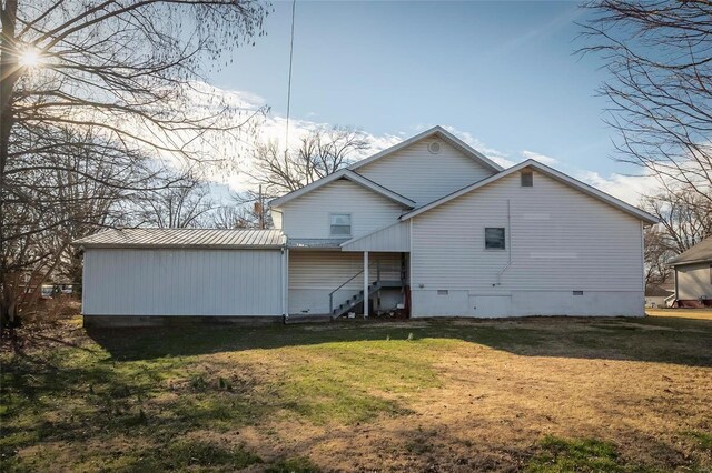 back of property with crawl space, metal roof, and a yard