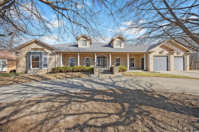 cape cod house with brick siding, a shingled roof, a porch, concrete driveway, and a garage