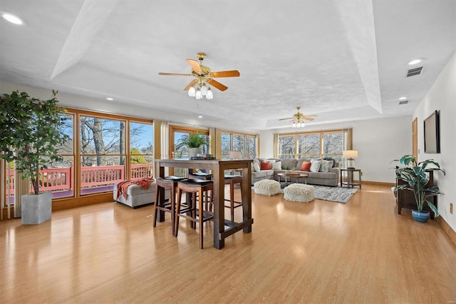 dining area with plenty of natural light, baseboards, a tray ceiling, and wood finished floors