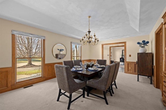 dining room with light colored carpet, visible vents, and wainscoting