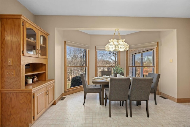 dining room featuring a notable chandelier, a healthy amount of sunlight, visible vents, and baseboards