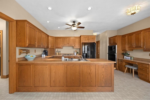 kitchen featuring a peninsula, brown cabinetry, black appliances, a ceiling fan, and a sink