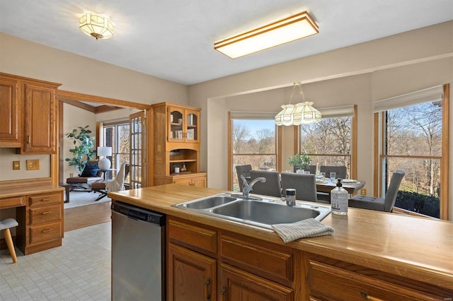 kitchen featuring brown cabinetry, a sink, plenty of natural light, and stainless steel dishwasher