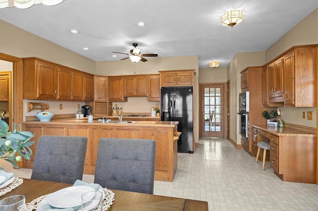 kitchen featuring black fridge with ice dispenser, brown cabinets, light countertops, and ceiling fan