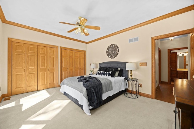 bedroom with visible vents, multiple closets, carpet flooring, and crown molding