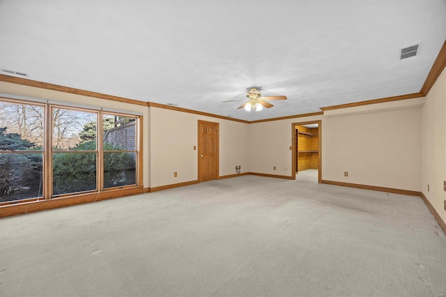 empty room featuring baseboards, light colored carpet, visible vents, and ornamental molding