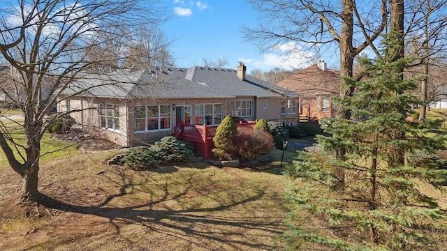 rear view of house with a wooden deck, a yard, and a chimney