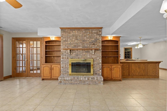 unfurnished living room with a fireplace, built in features, a ceiling fan, and baseboards