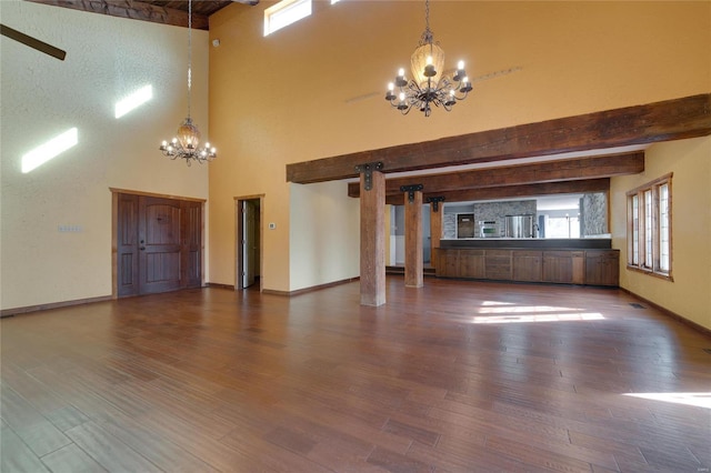 unfurnished living room featuring beamed ceiling, a notable chandelier, wood finished floors, and baseboards