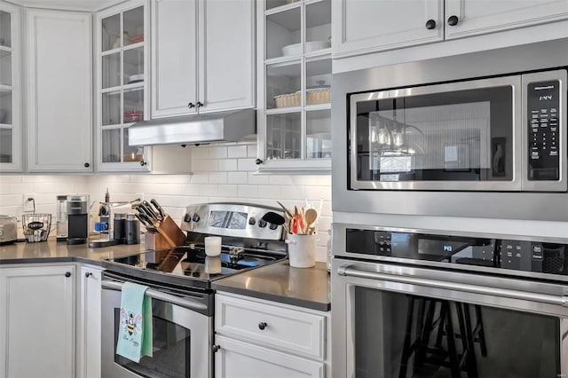 kitchen with under cabinet range hood, white cabinets, backsplash, and appliances with stainless steel finishes