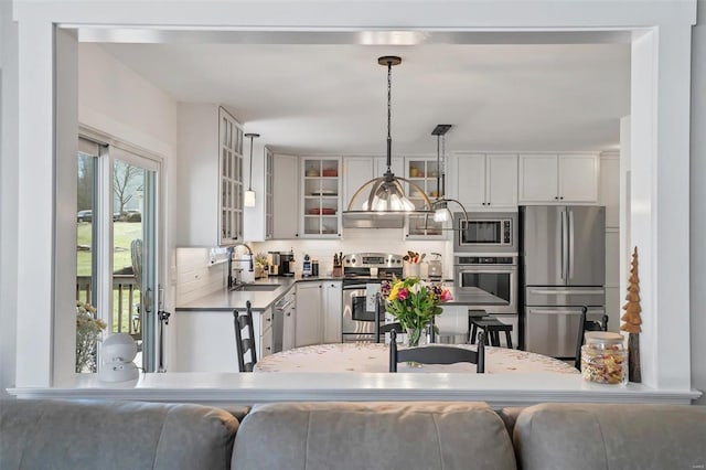 kitchen featuring white cabinets, glass insert cabinets, appliances with stainless steel finishes, and a sink