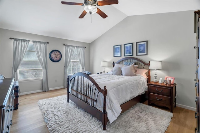 bedroom featuring light wood finished floors, ceiling fan, baseboards, and lofted ceiling