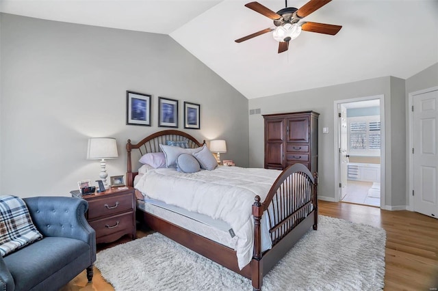 bedroom with baseboards, visible vents, light wood finished floors, ensuite bath, and lofted ceiling