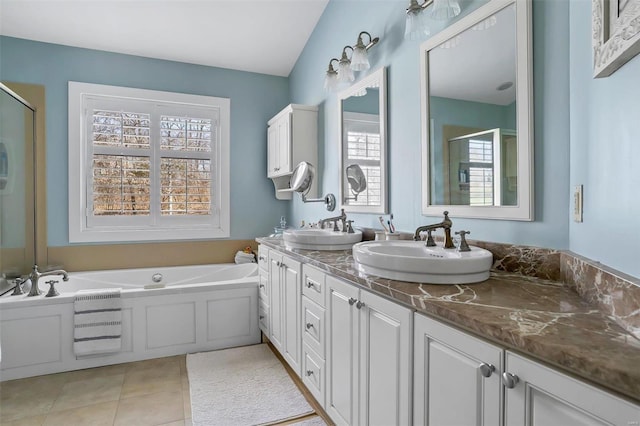 bathroom with double vanity, a stall shower, a sink, tile patterned floors, and a bath