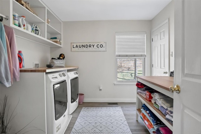 clothes washing area featuring baseboards, dark wood finished floors, laundry area, and washing machine and clothes dryer