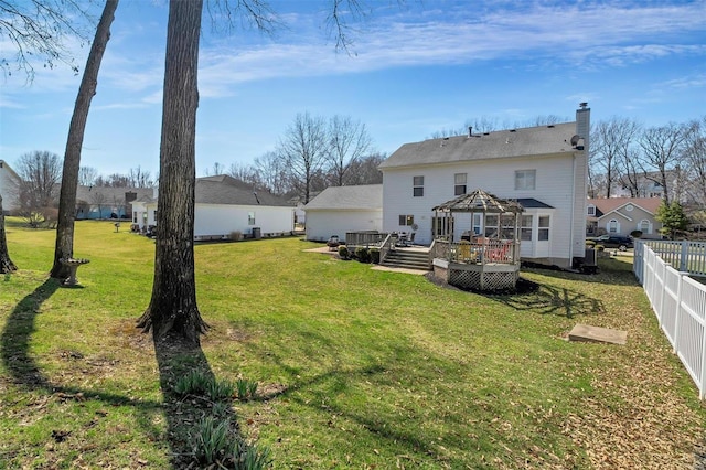 rear view of property with a deck, fence, a gazebo, a yard, and a chimney