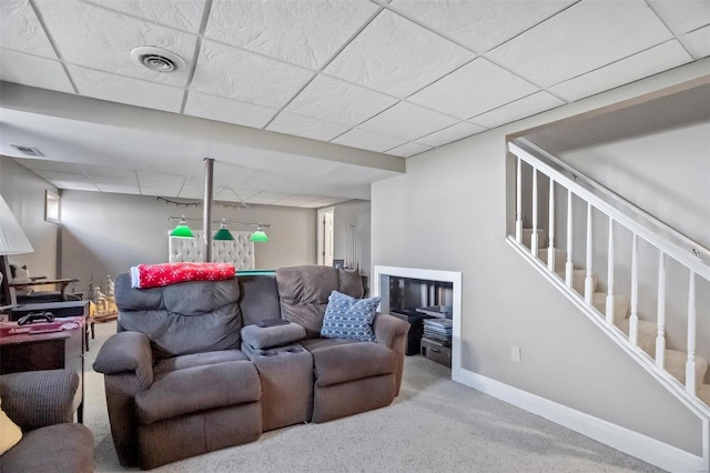 carpeted living room with a paneled ceiling, visible vents, baseboards, and stairs