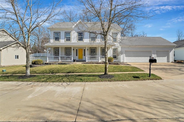 colonial home with concrete driveway, a porch, a front lawn, and an attached garage