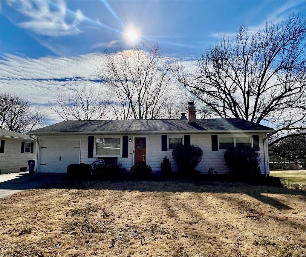 ranch-style house featuring driveway, brick siding, a chimney, and an attached garage