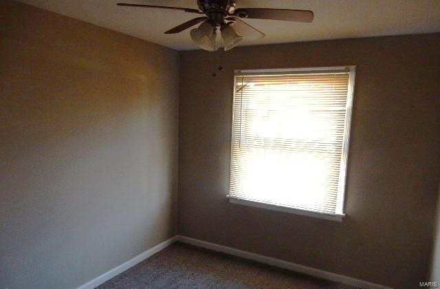 carpeted spare room with a ceiling fan and baseboards