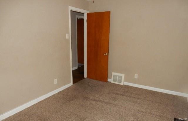 carpeted spare room featuring visible vents and baseboards