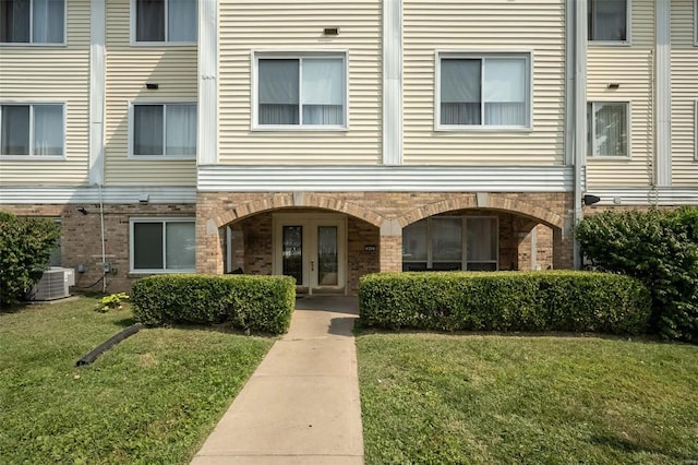 view of front of home with french doors, brick siding, central AC unit, and a front yard