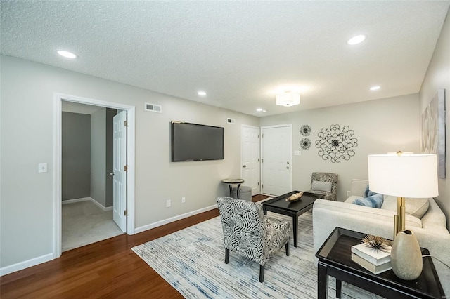 living room with wood finished floors, baseboards, visible vents, recessed lighting, and a textured ceiling