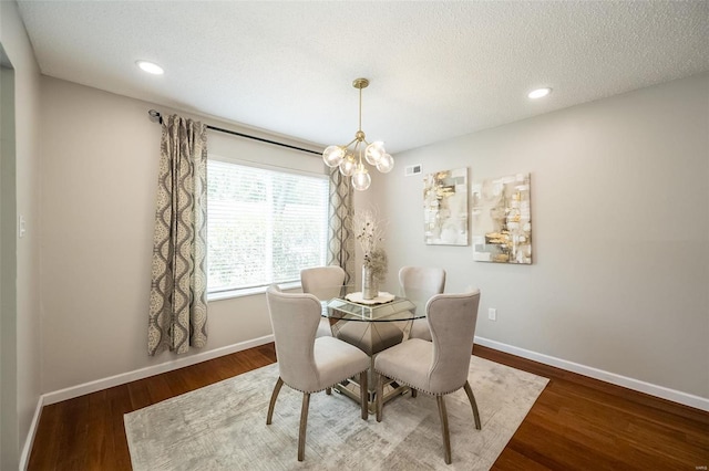 dining area featuring a notable chandelier, wood finished floors, baseboards, and a textured ceiling