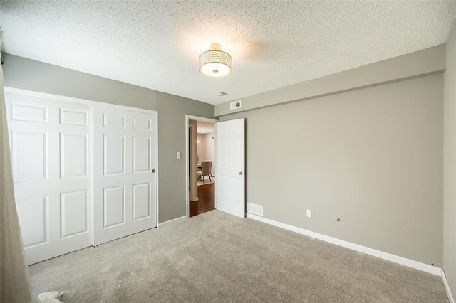 unfurnished bedroom featuring carpet, visible vents, baseboards, a closet, and a textured ceiling