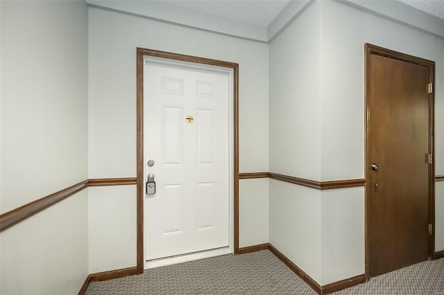 doorway featuring light colored carpet and baseboards