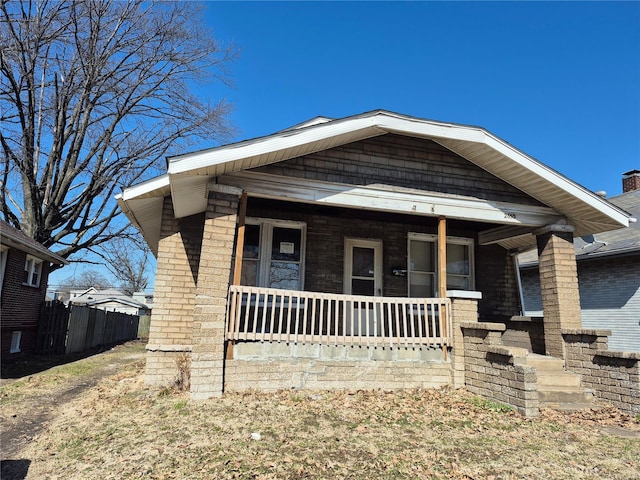 view of front of property with fence, brick siding, and covered porch