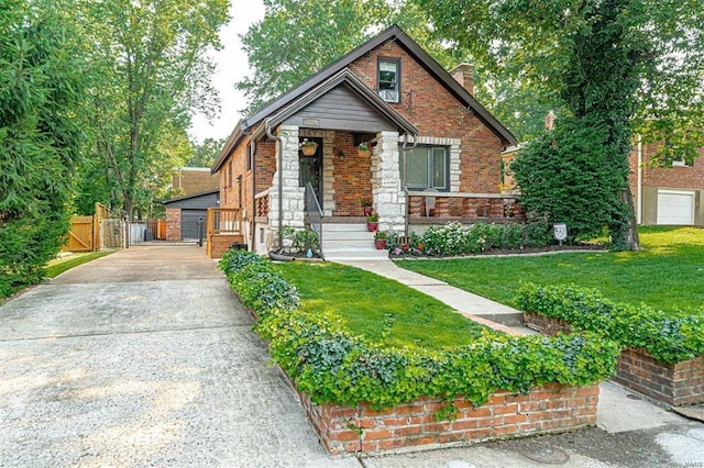 view of front of property featuring a front yard, a gate, a chimney, stone siding, and brick siding