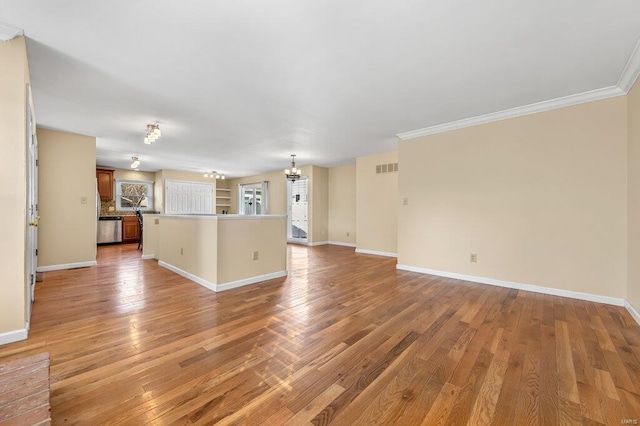 unfurnished living room featuring crown molding, baseboards, light wood-type flooring, and an inviting chandelier