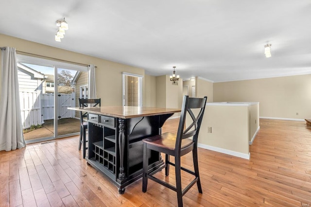 dining area with light wood-type flooring, baseboards, and a chandelier