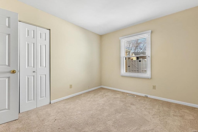 carpeted empty room featuring baseboards and visible vents