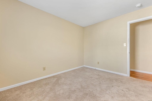 spare room featuring light carpet and baseboards