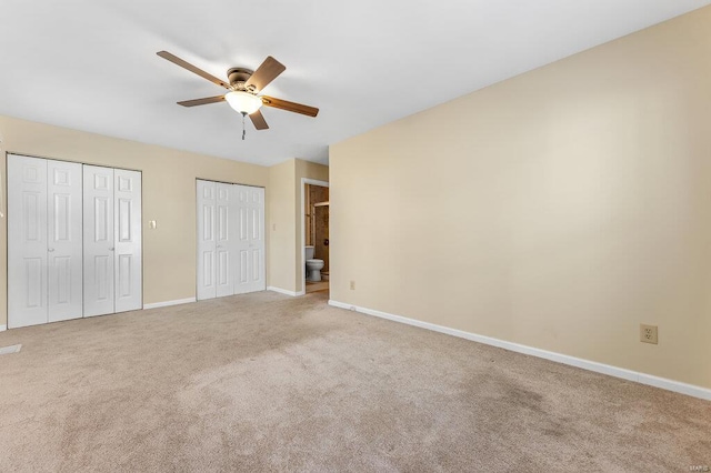 unfurnished bedroom featuring light colored carpet, baseboards, two closets, and ceiling fan