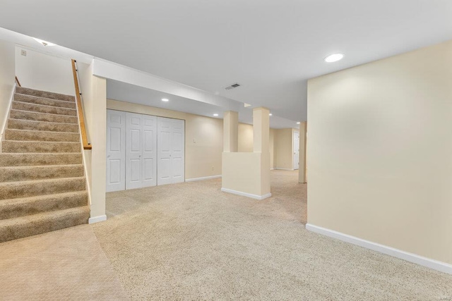 finished basement with stairs, visible vents, baseboards, and carpet flooring