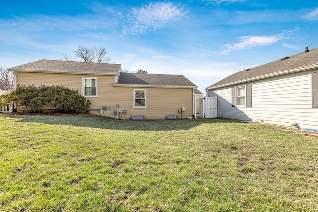 rear view of house with a gate, a yard, fence, and cooling unit