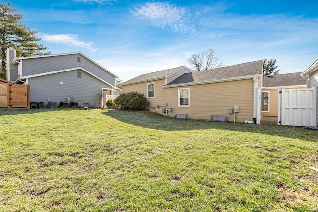 back of house featuring fence, a yard, and a gate