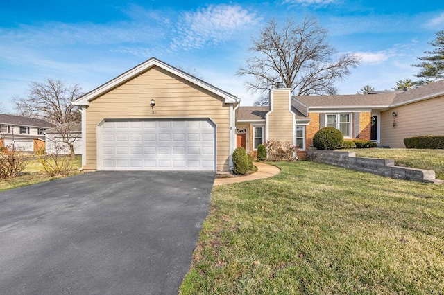 single story home featuring brick siding, a front yard, a chimney, driveway, and an attached garage