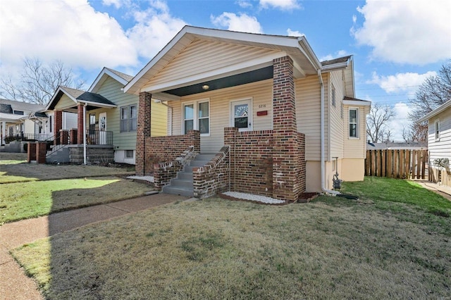 view of front of house featuring covered porch, a front yard, and fence