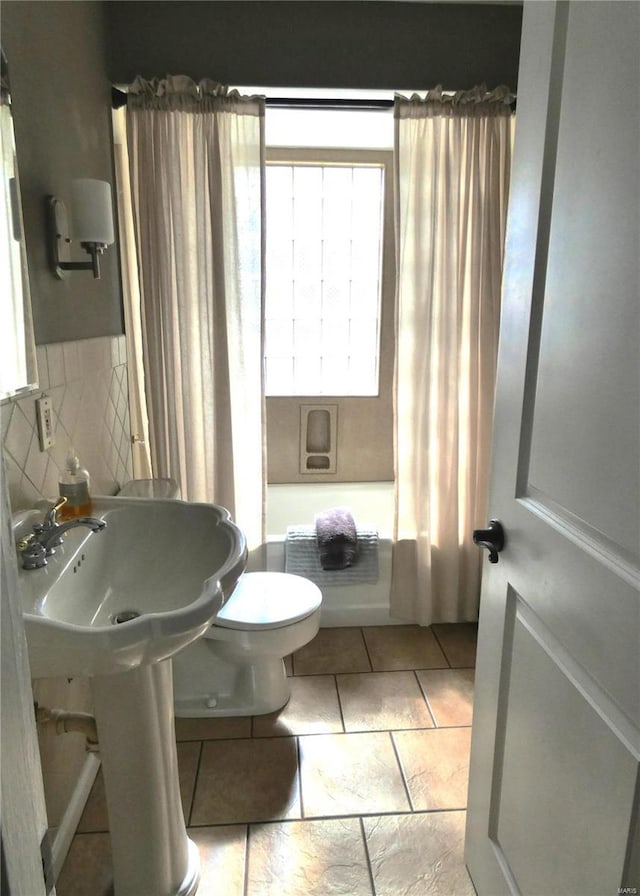 full bath featuring toilet, shower / bathtub combination with curtain, and tasteful backsplash