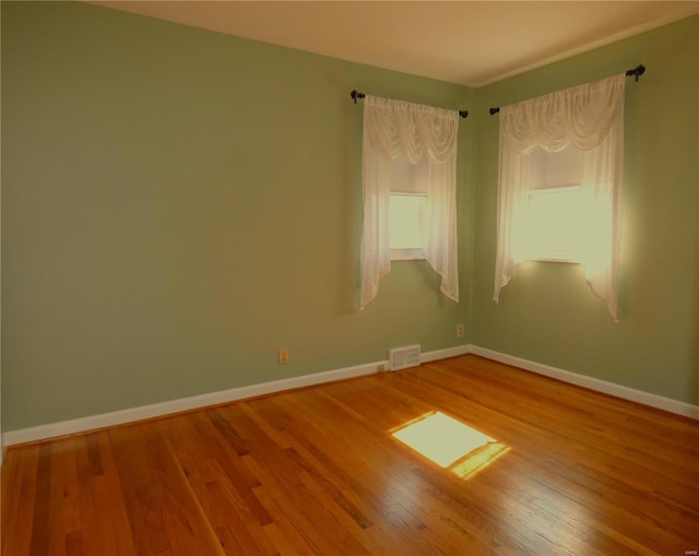 spare room featuring visible vents, baseboards, and hardwood / wood-style floors