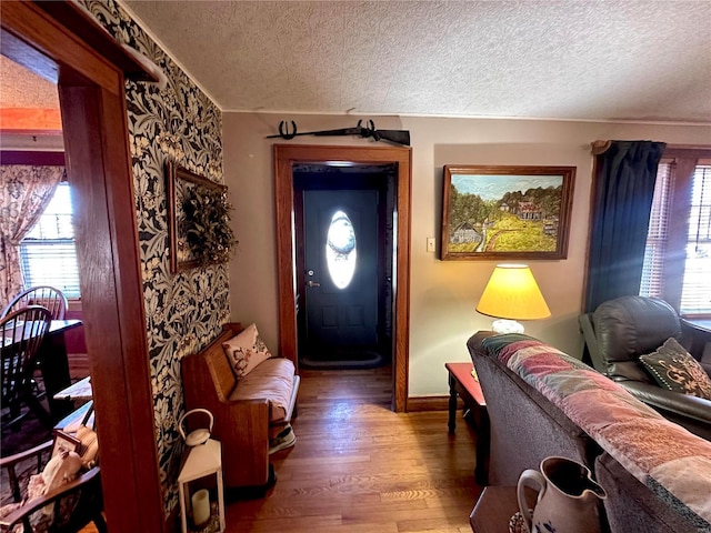 foyer with plenty of natural light, wood finished floors, baseboards, and a textured ceiling