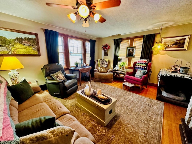 living area with a textured ceiling, ceiling fan, and wood finished floors