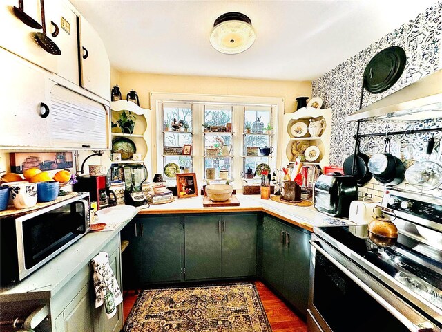 kitchen with dark wood finished floors, range hood, light countertops, and electric stove