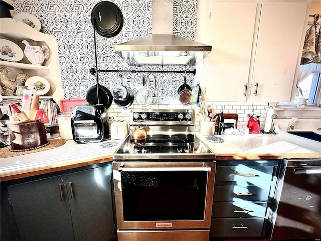 kitchen with tasteful backsplash, stainless steel electric range oven, wall chimney exhaust hood, and light countertops