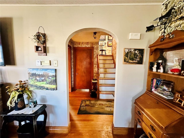 corridor featuring stairs, wood finished floors, arched walkways, and baseboards